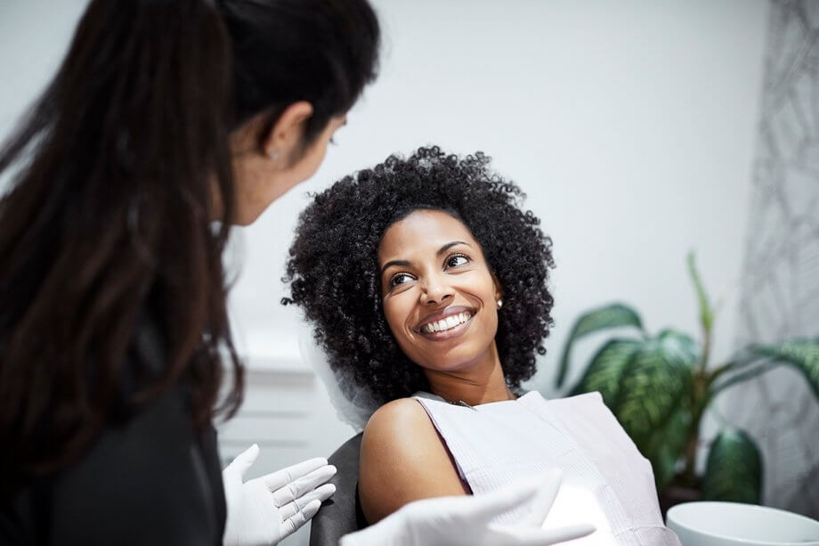 woman sitting in dental chair talking to dentist