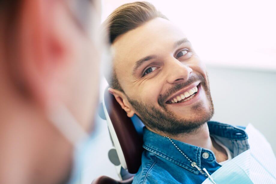 Man in Dental Chair Smiling After Dental Implants